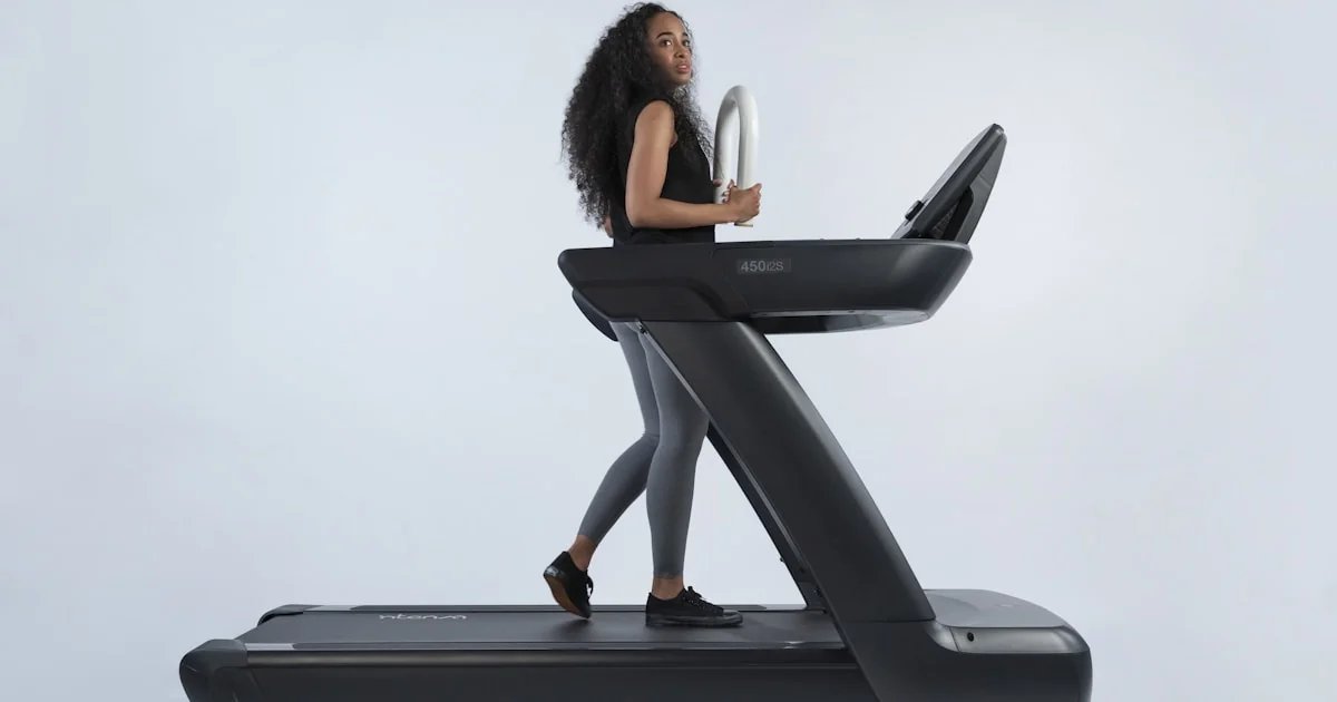 Persoană alergând pe bandă de alergat într-un spațiu de fitness modern
