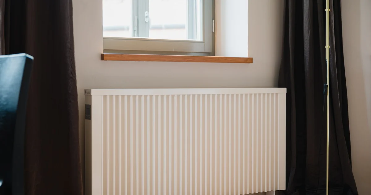 Calorifer electric alb sub fereastră, într-un interior modern