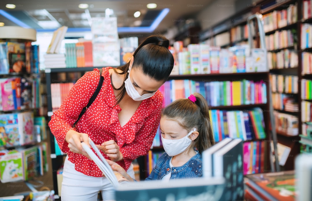 Copil citind o carte colorată, aproape de fereastră