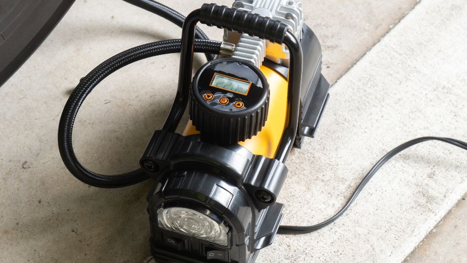 Compresor portabil lângă roată de mașină