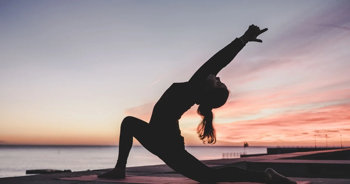 Persoană în poziție de yoga pe saltea întinsă