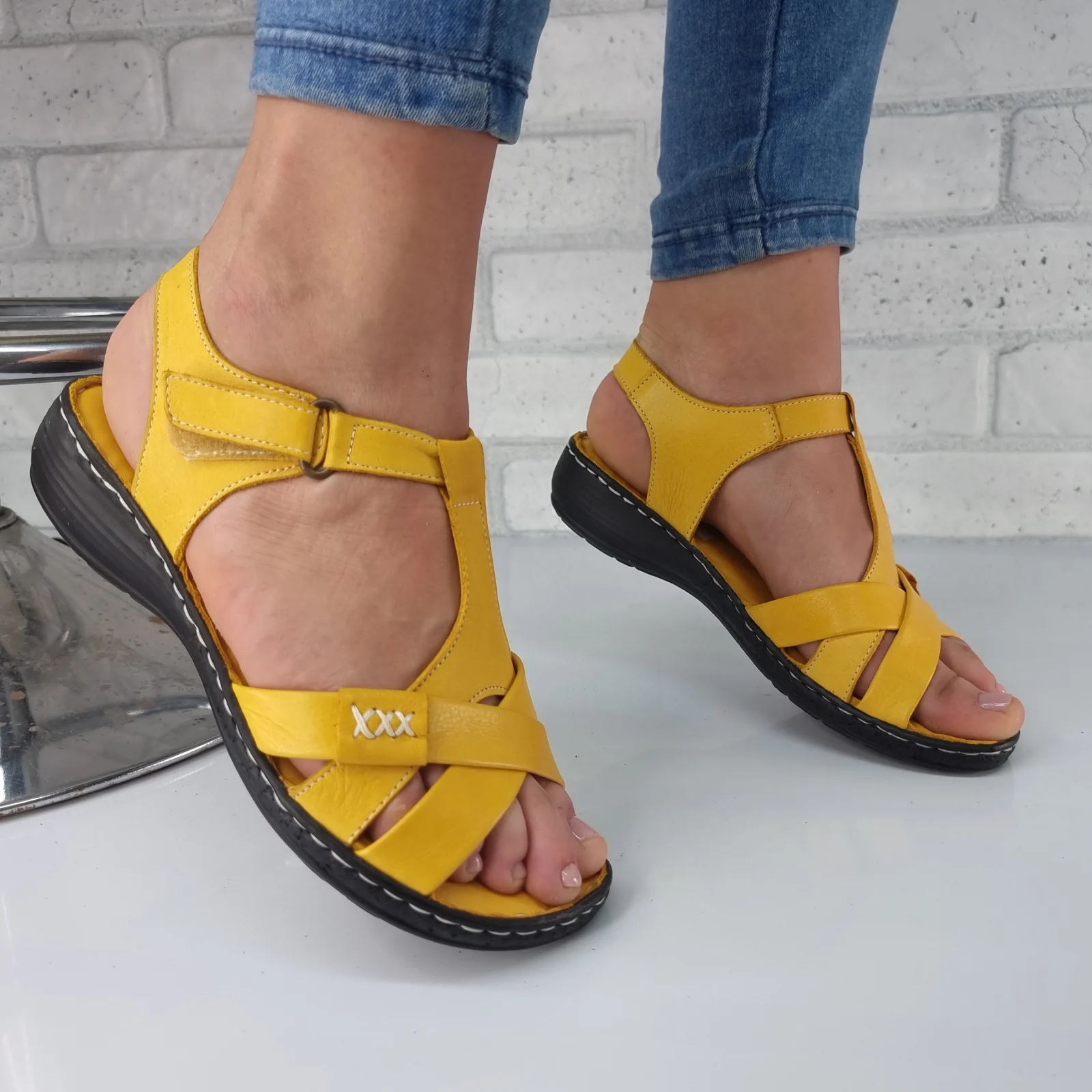 Perechi de sandale damă aranjate pe un fundal de lemn deschis